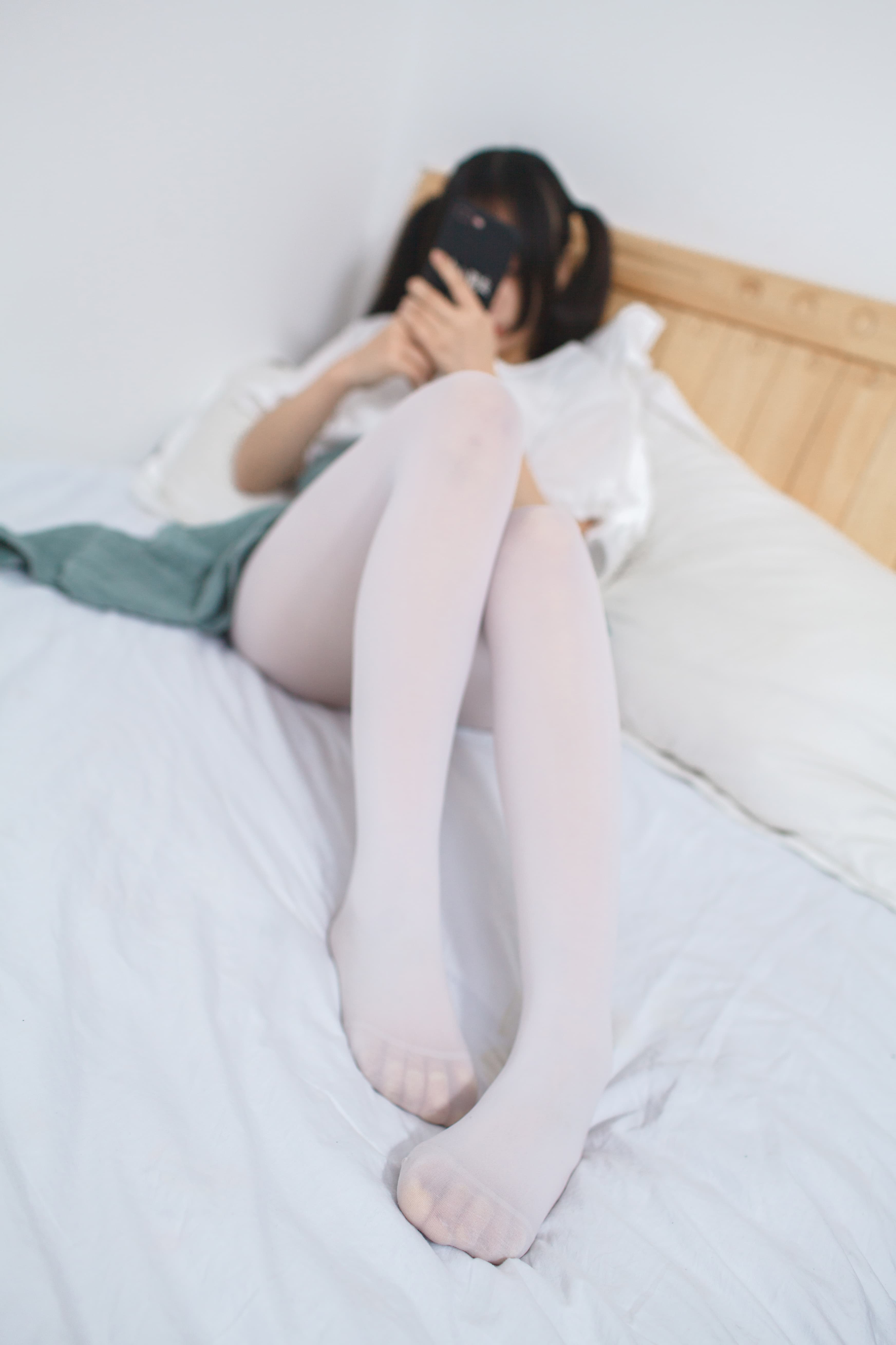 Bare feet peeking from under a blanket with nylon rolled down to reveal warm ankles